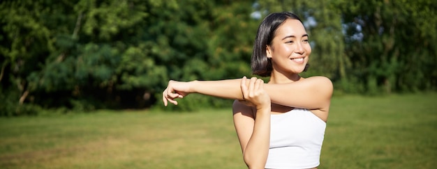 Foto grátis retrato de uma jovem mulher de fitness esticando os braços antes da sessão de treinamento de um evento esportivo em