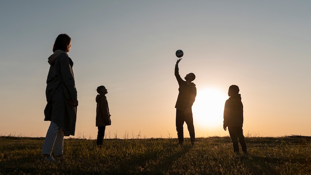 Foto grátis silhueta de família de tiro completo se divertindo ao pôr do sol