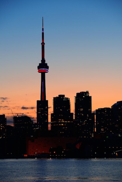 Foto grátis silhueta do horizonte da cidade de toronto ao pôr do sol sobre o lago com arranha-céus urbanos.