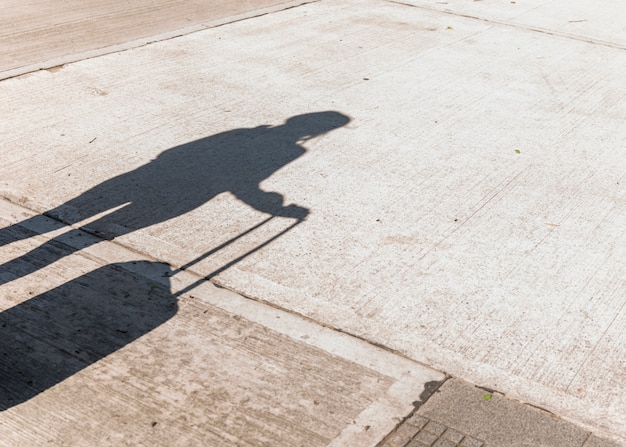 Foto grátis sombra de uma turista feminina segurando bagagem de rodas no asfalto