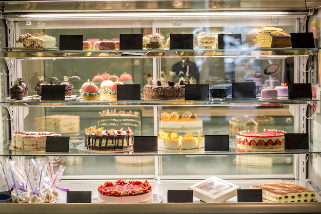 Foto grátis vitrine de vidro de pastelaria com variedade de bolos e doces frescos. sobremesas doces populares oferecidas para venda