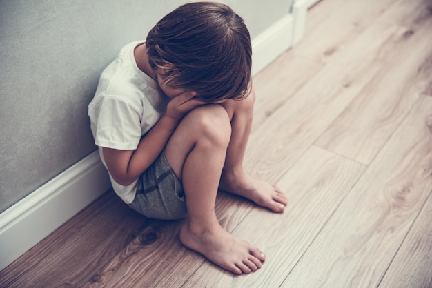 Foto o choro do menino cobriu o rosto com as mãos. criança estressada. violência doméstica familiar e violência do conceito de agressão. conceito de bullying, depressão, estresse ou frustração