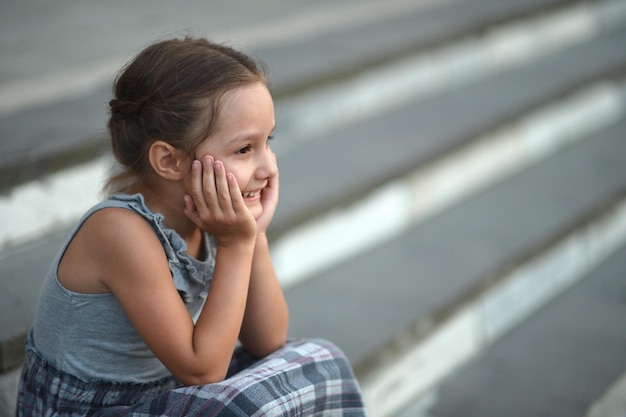 Foto retrato de uma menina sorridente sentada nas escadas