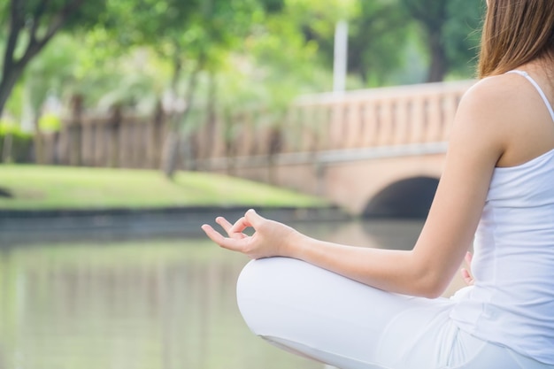 Foto seção do meio de uma mulher meditando junto a uma lagoa