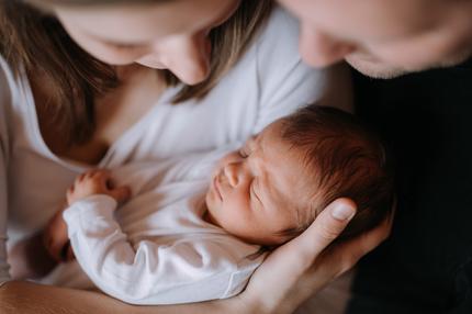 RSV-Antikörper: A close-up of a mother and father holding a newborn baby son at home.