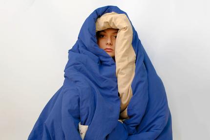 Psychologie: A portrait of a woman covering self with a blanket showing only her face