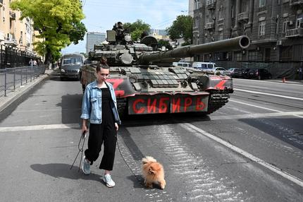 Wagner-Gruppe in Russland: Eine Frau mit einem Hund geht an einem Panzer vorbei, während Kämpfer der privaten Söldnergruppe Wagner in einer Straße in der Nähe des Hauptquartiers des südlichen Militärbezirks in der Stadt Rostow am Don, Russland, am 24. Juni eingesetzt werden