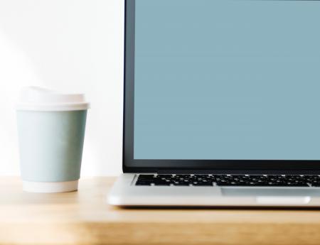 Macbook Pro Beside Gray Disposable Cup on Brown Wooden Surface