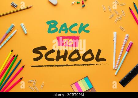 Stock photo of the concept back to school with lettering written on a yellow background and several stationery objects Stock Photo