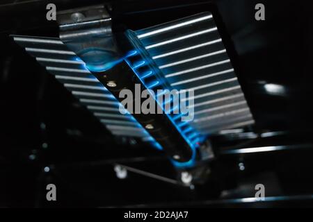 Blue flames burning inside a gas oven close up Stock Photo