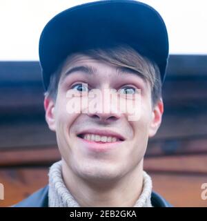 Portrait of a young happy guy 20-21 years old in a cap Stock Photo