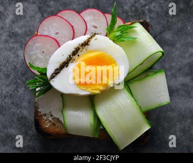 Egg Toast with Cucumber, Cream Сheese and Rye Bread on a Dark Background. Healthy Food Concept.Top View.Close-up Stock Photo