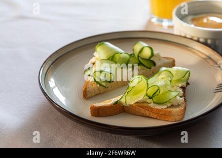 Cucumber and cream cheese toast on a plate. Healthy vegetarian diet concept. Stock Photo