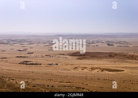 A desert landscape viewed from the Natural Arch of Riyadh. A plain surrounded by the mountain ridge - a Martian-like landscape. Stock Photo