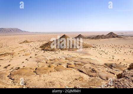 A desert landscape viewed from the Natural Arch of Riyadh. A plain surrounded by the mountain ridge - a Martian-like landscape. Stock Photo