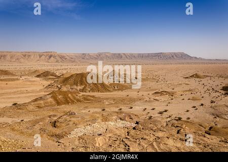 A desert landscape viewed from the Natural Arch of Riyadh. A plain surrounded by the mountain ridge - a Martian-like landscape. Stock Photo