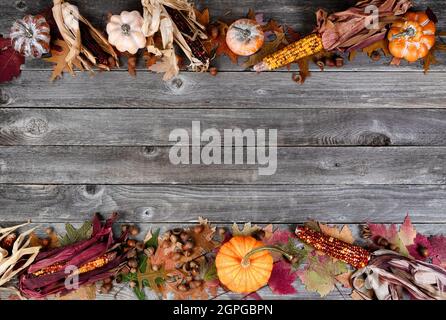 Top and bottom border of real whole pumpkin, corn, acorns and foliage leaves on weathered wooden planks for the Autumn holiday season of Halloween or Stock Photo