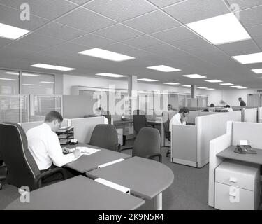 1989, historical, company employees working at desks in shared cubicles, in an open office set-up common in this era, England, UK, with the manager sitting at a large semi-circular desk, looking out over the floor. Stock Photo