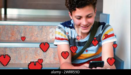 Digital composite of a Caucasian boy sitting in the stairs smiling while texting and digital hearts Stock Photo