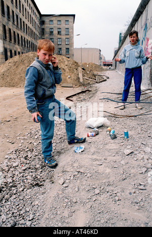 The Fall of the Berlin wall, 1989. A children spray paint rocks to sell as genuine graffiti from the wall. Stock Photo