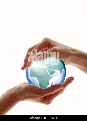 Two hands encircling glass globe isolated against white Stock Photo