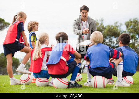 Coach talking to childrens soccer team Stock Photo