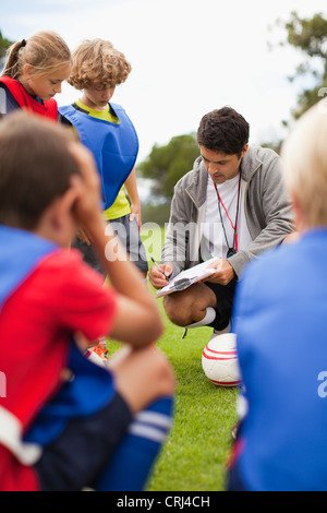 Coach talking to childrens soccer team Stock Photo