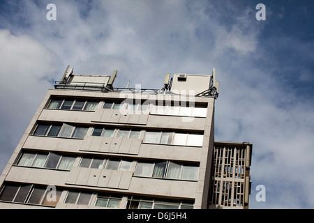 Mobile phone masts on an office block in London, England against a cloudy sky. Stock Photo