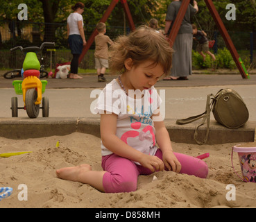 Little girl playing in sand at playground Stock Photo