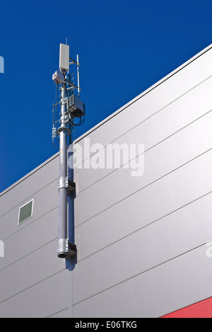 GSM Antenna. Mobile phone signal repeater system installed on the roof top of industrial building. Stock Photo