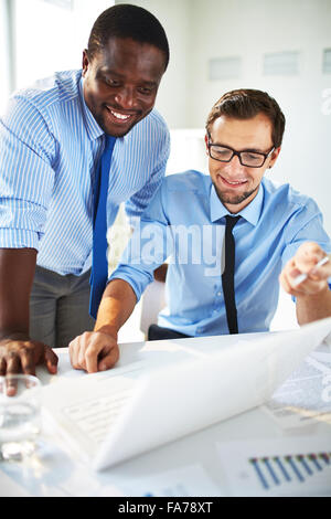 Two handsome businessmen working together on a project sitting at a table in the office Stock Photo