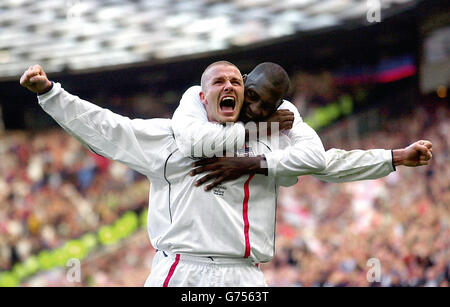 England's captain David Beckham (front) celebrates with team-mate Emile Heskey after scoring the equaliser from a free kick against Greece in the dying seconds of the FIFA World Cup European Qualifying Group Nine match at Old Trafford, Manchester. Stock Photo