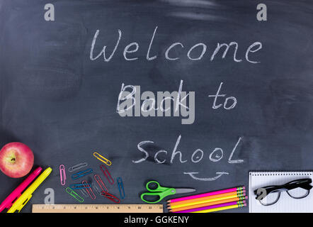 Back to school concept with supplies on chalkboard with written message to welcome students. Stock Photo