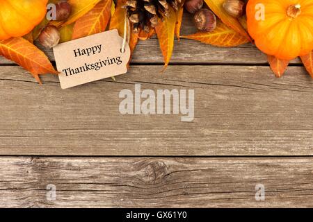 Happy Thanksgiving tag with autumn top border of pumpkins, leaves and nuts on a rustic wooden background Stock Photo