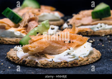 Salmon and cucumber canapes on oat cakes with black cracked pepper Stock Photo