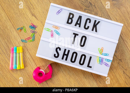 Back to school written on a modern light box on wood background, colorful supplies Stock Photo