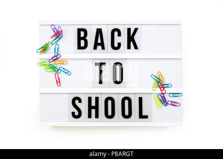 Back to school written on a modern light box on white background, colorful paper clips Stock Photo