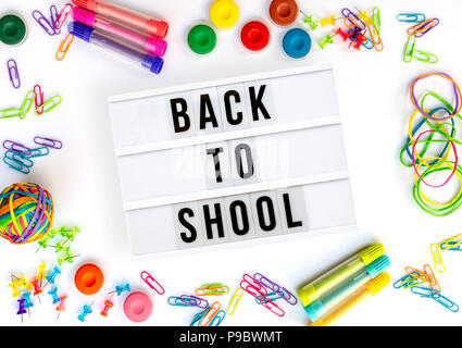 Back to school written in a light box, colorful school supplies isolated on white Stock Photo