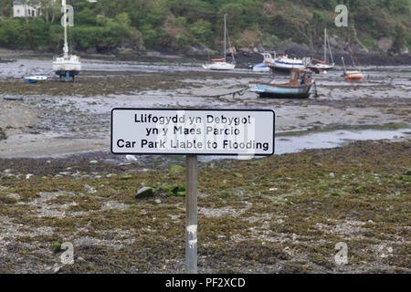 Boats in the harbor with a car park liable to flooding sign Stock Photo