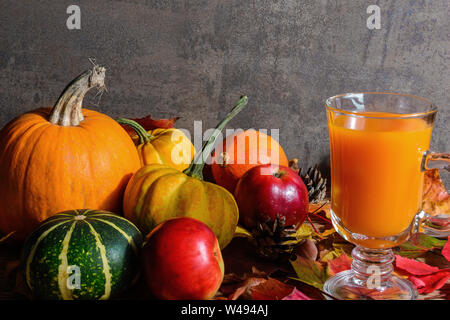 Thanksgiving Autumn Fall background with orange drink cocktail, harvested pumpkins, apples, nuts and maple leaves on rustic wooden table. top view wit Stock Photo