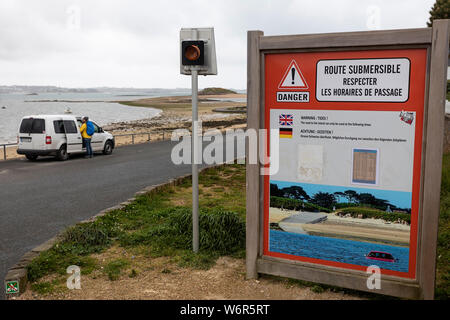 A car parked at Route submersible warning sign indicating that the road is liable to fllooding at high tide, Brittany, France Stock Photo