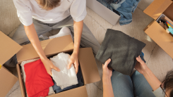 two people sorting through clothing and packing away into boxes