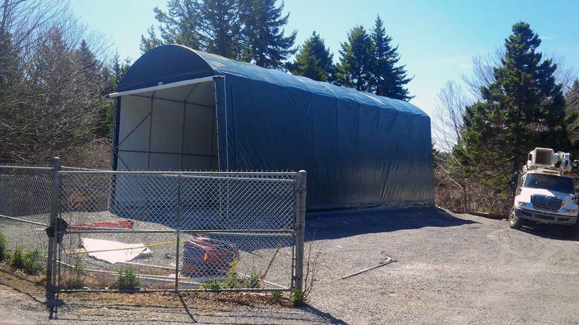 A truck is parked in front of a large blue building behind a chain link fence.