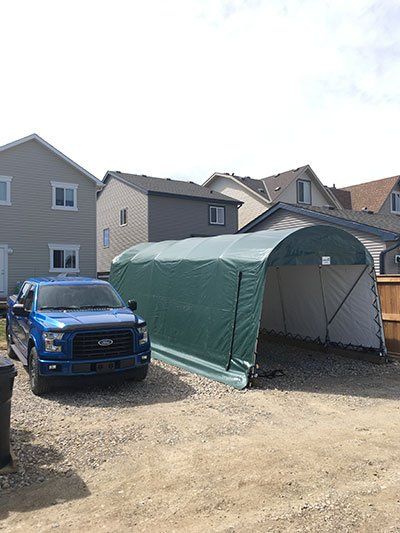 A blue truck is parked in front of a green tent.