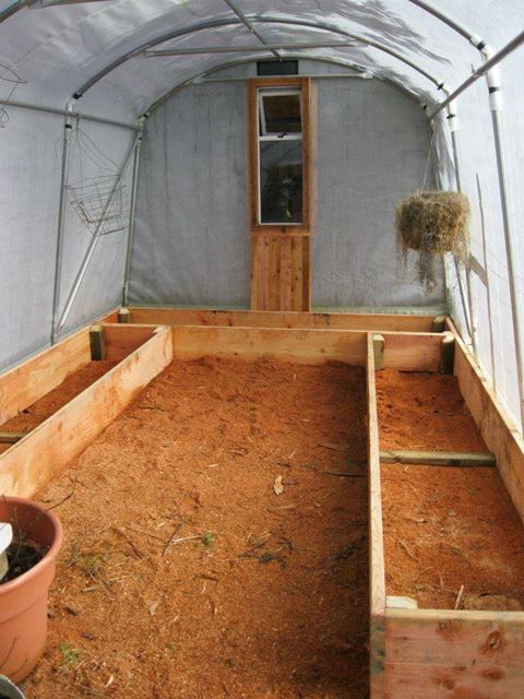 A greenhouse filled with wooden boxes and dirt