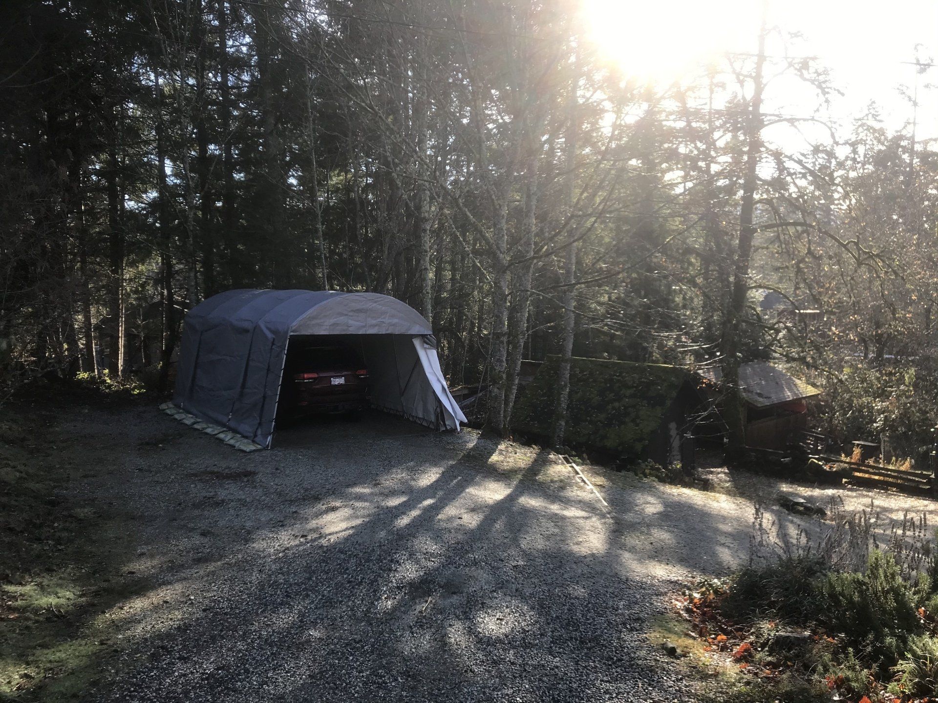 A car is parked in a garage in the woods.