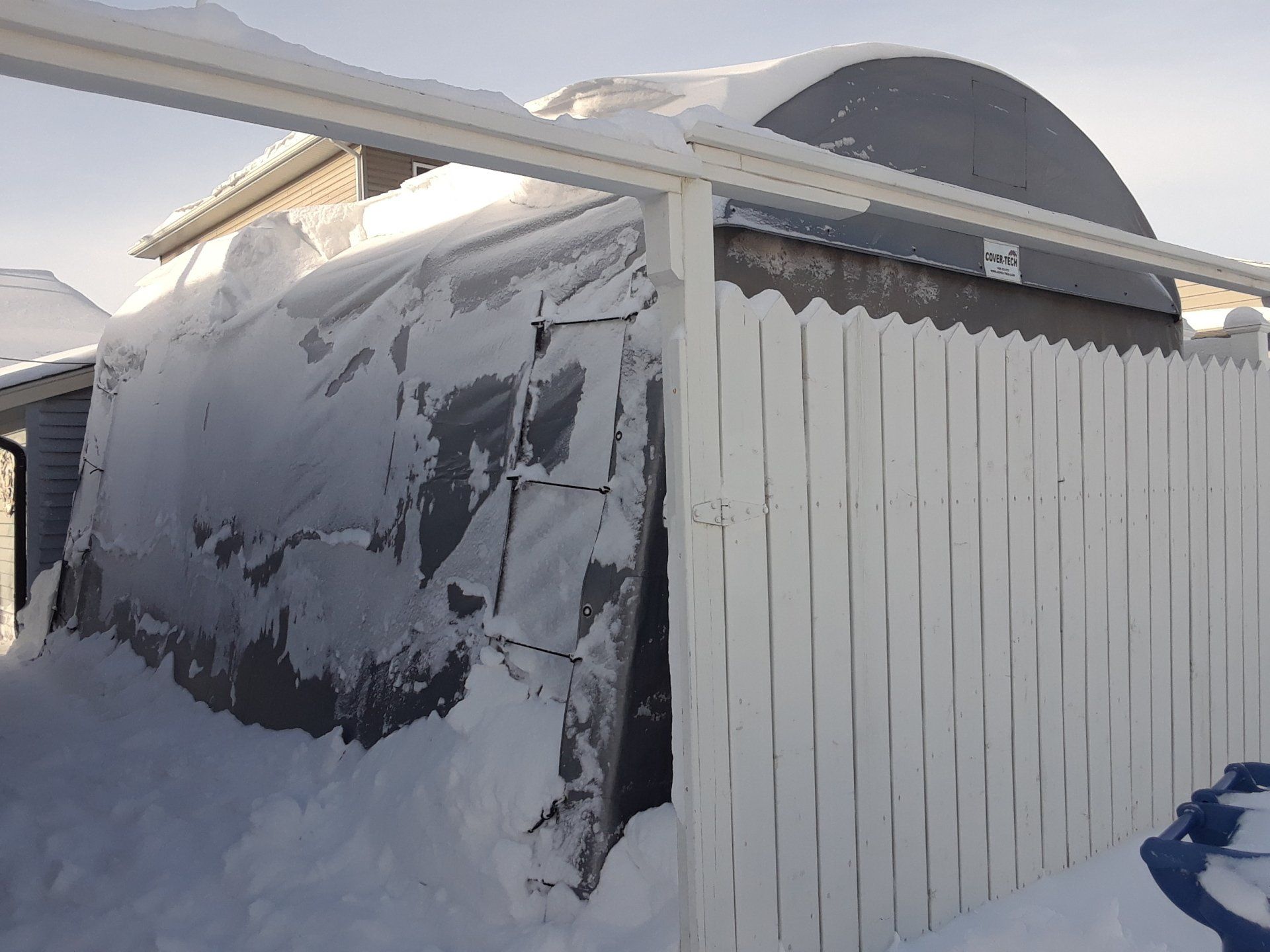 A snow covered building with a white fence in front of it