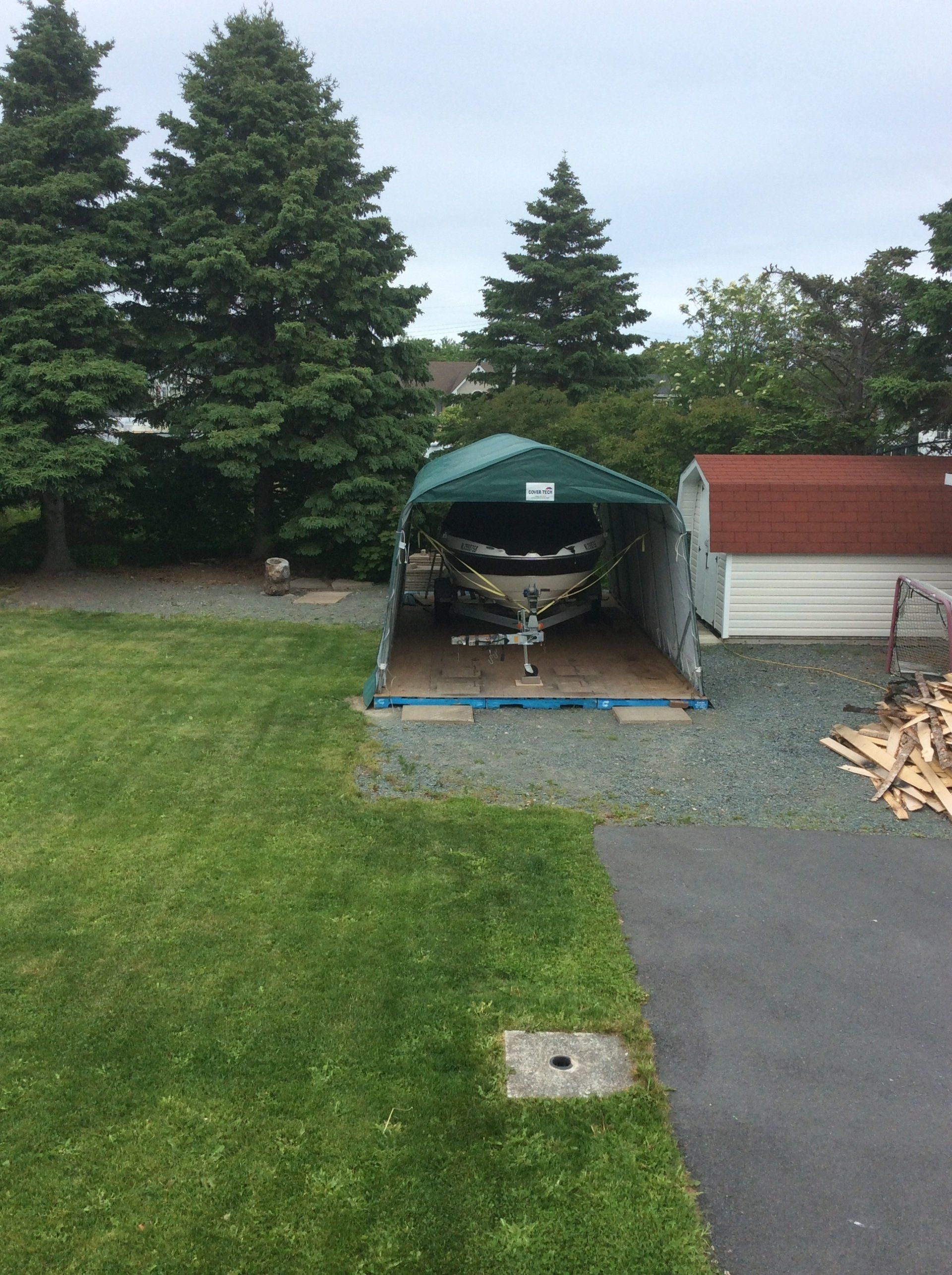 A boat is sitting under a green canopy in a garage.