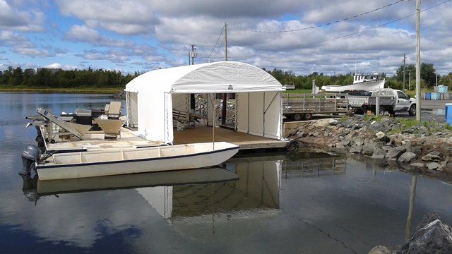 A boat is docked under a white tent in the water.