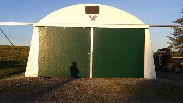 A white building with green doors and a basketball hoop on top